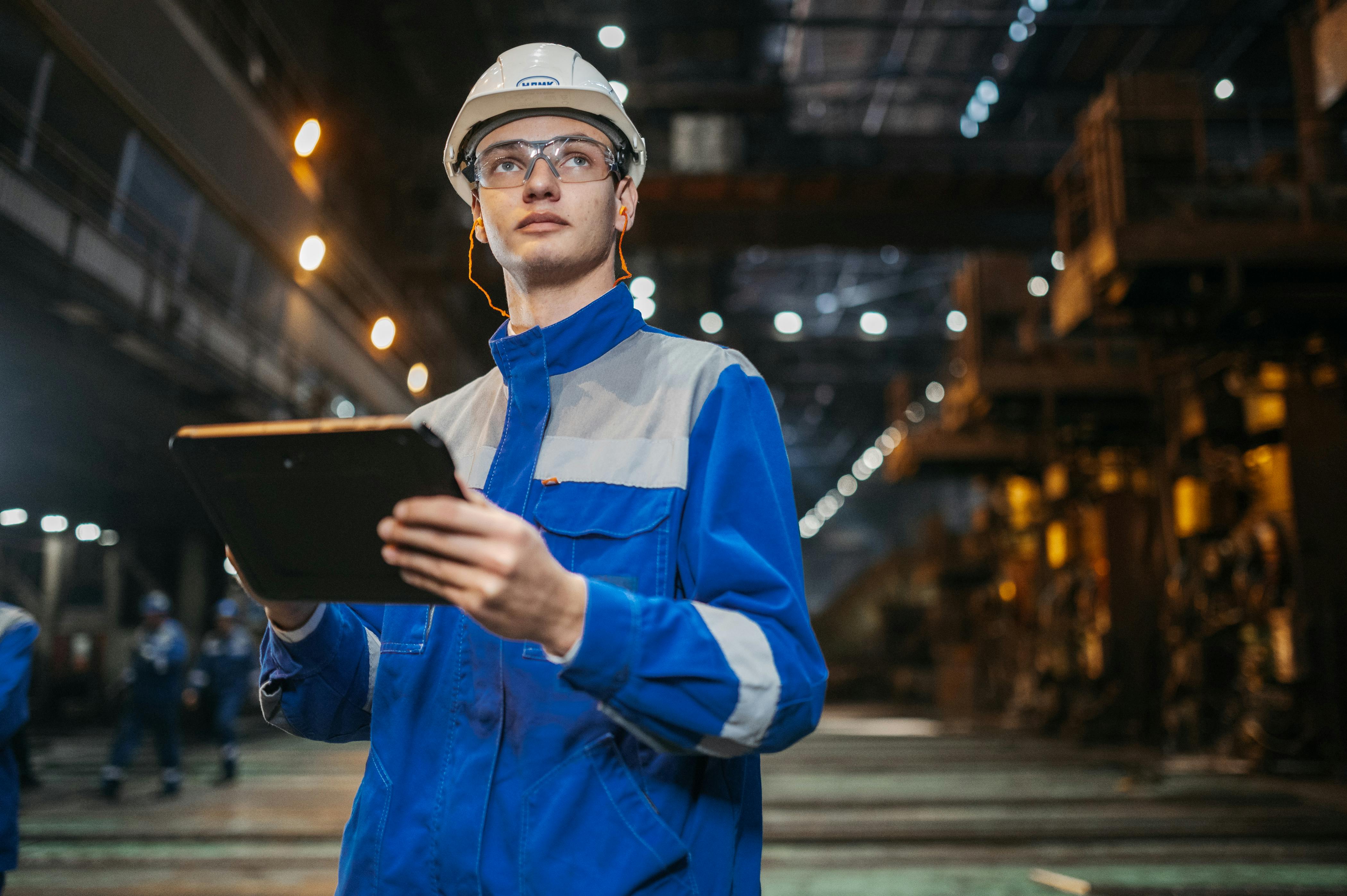 Engineer in an industrial production setting using a tablet.